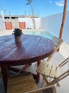 a wooden table with a potted plant and two chairs at La Conchita de Sisal 7 in Sisal