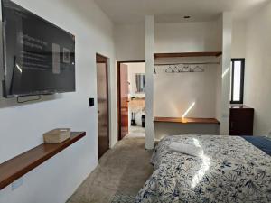 a bedroom with a bed and a flat screen tv at La Conchita de Sisal 7 in Sisal