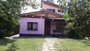 a pink house with a yard in front of it at La Carioca in Villa Gesell