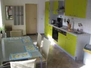 a kitchen with yellow cabinets and a table with chairs at Apartment mit Terrasse by Interhome in Sayda