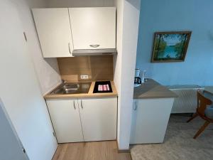 a small kitchen with white cabinets and a sink at Apartment Haus Budinger by Interhome in Alf