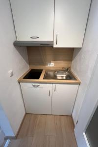 a small kitchen with a sink and white cabinets at Apartment Haus Budinger by Interhome in Alf