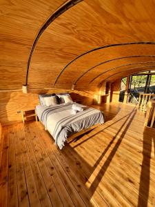 a bed in the middle of a room with wooden floors at Swiss Eco Lodge La Linda Loma - Olmué in Olmué