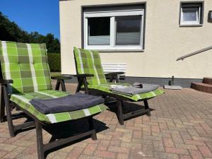 two green chairs and a table on a patio at Holiday Home Klosterwald by Interhome in Dargun