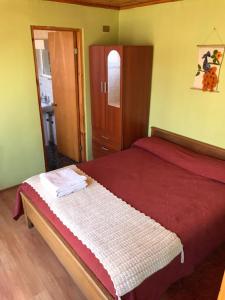 een slaapkamer met een bed met een rood dekbed bij Hostal Lucerna in Curanipe