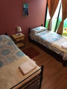 een slaapkamer met twee bedden en een tafel met een lamp bij Hostal Lucerna in Curanipe