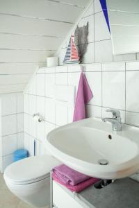 a white bathroom with a sink and a toilet at Apartment Fewo Dirks 2 by Interhome in Hemfurth-Edersee