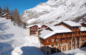 a building covered in snow in front of a mountain at Résidence Odalys Les Jardins de Val et Les Verdets in Val-d'Isère