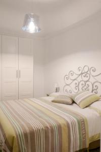 Dormitorio blanco con cama con manta a rayas en Your Sweet Home, en Génova