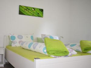 a bed with green and white pillows on it at Apartment FeWo Siebert by Interhome in Bad Brambach