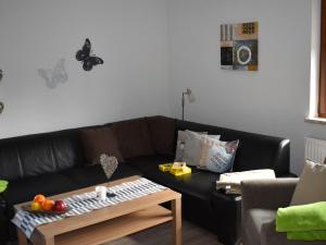 a living room with a black couch and butterflies on the wall at Apartment FeWo Siebert by Interhome in Bad Brambach