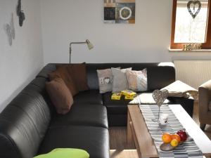 a black leather couch in a living room with a table at Apartment FeWo Siebert by Interhome in Bad Brambach +35 photos
