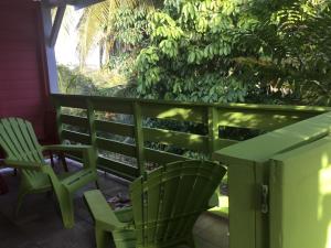 twee groene stoelen en een tafel op een veranda bij Résidence rose Cannelle in Grand-Bourg +4 foto's