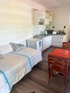 a bedroom with a bed and a table and a kitchen at Cabaña Habibi in Potrero de Garay