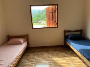 two beds in a room with a window at Paraty Prime House in Paraty