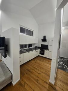 a white kitchen with white cabinets and a wooden floor at Stylische Ferienwohnung 2 in Salzburg