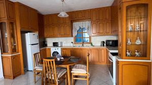 a kitchen with wooden cabinets and a table with chairs at Dina's Beach House in Karpathos