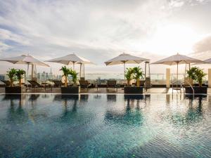 une piscine avec tables et parasols sur un bâtiment dans l'établissement The Canvas Dubai - MGallery Hotel Collection, à Dubaï