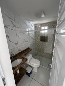 een witte badkamer met een toilet en een wastafel bij Flats Brisa Antunes in Maragogi +20 foto's