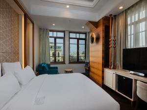 een slaapkamer met een groot wit bed en een flatscreen-tv bij Mercure Istanbul Sirkeci in Istanbul