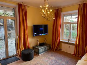 een woonkamer met oranje gordijnen en een flatscreen-tv bij Villa Marktresidenz - Ihre Ferienwohnungen im Herzen von Berchtesgaden in Berchtesgaden
