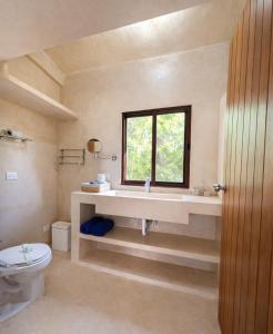 een badkamer met een wastafel en een toilet en een raam bij Island Escape for Groups Hosted by Atenea Holbox in Holbox Island