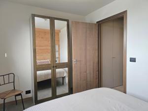 una camera da letto con un letto, una sedia e uno specchio di Moda Apartments Cimaboschi a Sestriere Altre 11 foto