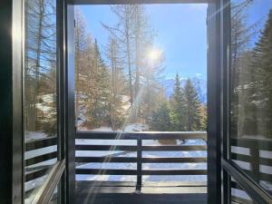 a window with a view of a snow covered forest at Moda Apartments Cimaboschi in Sestriere