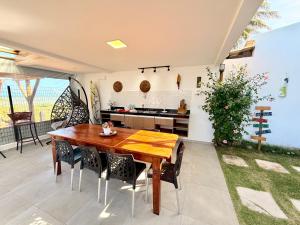 a kitchen and dining room with a wooden table and chairs at Roraimar Prime Maragogi - Beira Mar in Maragogi