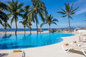 a pool on the beach with palm trees and chaise lounge chairs at Krystal Vallarta in Puerto Vallarta