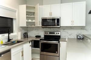 a white kitchen with a stove and a microwave at Havilah's Place Regina in Regina