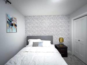 ein Schlafzimmer mit einem großen weißen Bett mit einer Akzentwand in der Unterkunft Havilah's Place Regina in Regina