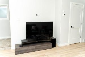 a living room with a flat screen tv on a stand at Havilah's Place Regina in Regina