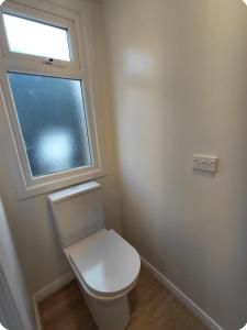 a white toilet in a bathroom with a window at Cow & Calf Cottages- bike wineries & relax in rural location Napier 15 mins in Puketapu