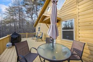 un tavolo in vetro con sedie e un ombrellone su una terrazza di Mountain Cabin Fireplace Views Fire Pit a Sautee Nacoochee