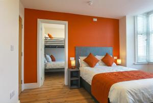 a bedroom with orange walls and a bed with orange pillows at Thorpe Lodge Hotel in Peterborough