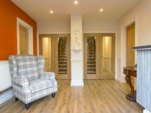 a living room with a chair and a piano at Thorpe Lodge Hotel in Peterborough