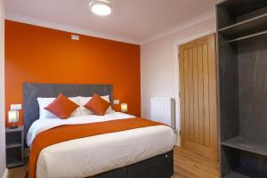 a bedroom with a bed with an orange wall at Thorpe Lodge Hotel in Peterborough