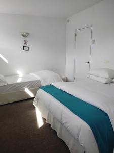 een witte slaapkamer met twee bedden en een raam bij De Gino Hostal in El Cerrillo +23 foto's