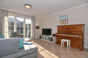 a living room with a piano and a couch at Gartenweg 3d in Tinnum