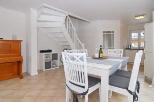a white dining room with a white table and chairs at Gartenweg 3d in Tinnum