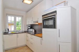 a kitchen with white cabinets and a microwave at Gartenweg 3d in Tinnum +11 photos