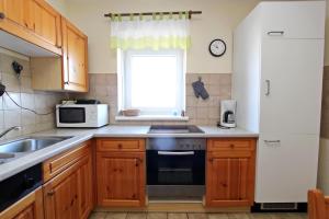 eine Küche mit einer Spüle, einem Herd und einem Fenster in der Unterkunft Silbermöwe in Hörnum