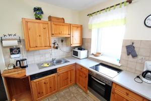 eine Küche mit Holzschränken, Spüle und Mikrowelle in der Unterkunft Silbermöwe in Hörnum