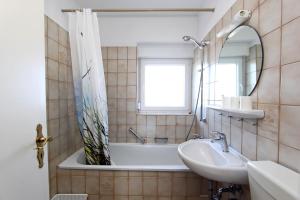 ein Badezimmer mit Badewanne, Waschbecken und Spiegel in der Unterkunft Silbermöwe in Hörnum