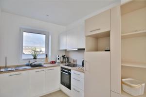 a white kitchen with white cabinets and a window at City Marina, CM24b in Cuxhaven