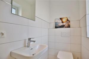 a white bathroom with a sink and a mirror at City Marina, CM24b in Cuxhaven +18 photos