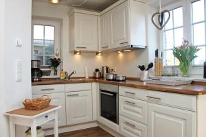 a kitchen with white cabinets and a counter top at Haus Clara in Hörnum