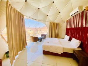 een slaapkamer met een bed en een groot raam bij Desert Stars Bubble Camp Wadi Rum in Wadi Rum