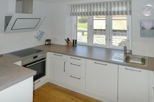 a kitchen with white cabinets and a sink at Simons Hüs in Oldsum